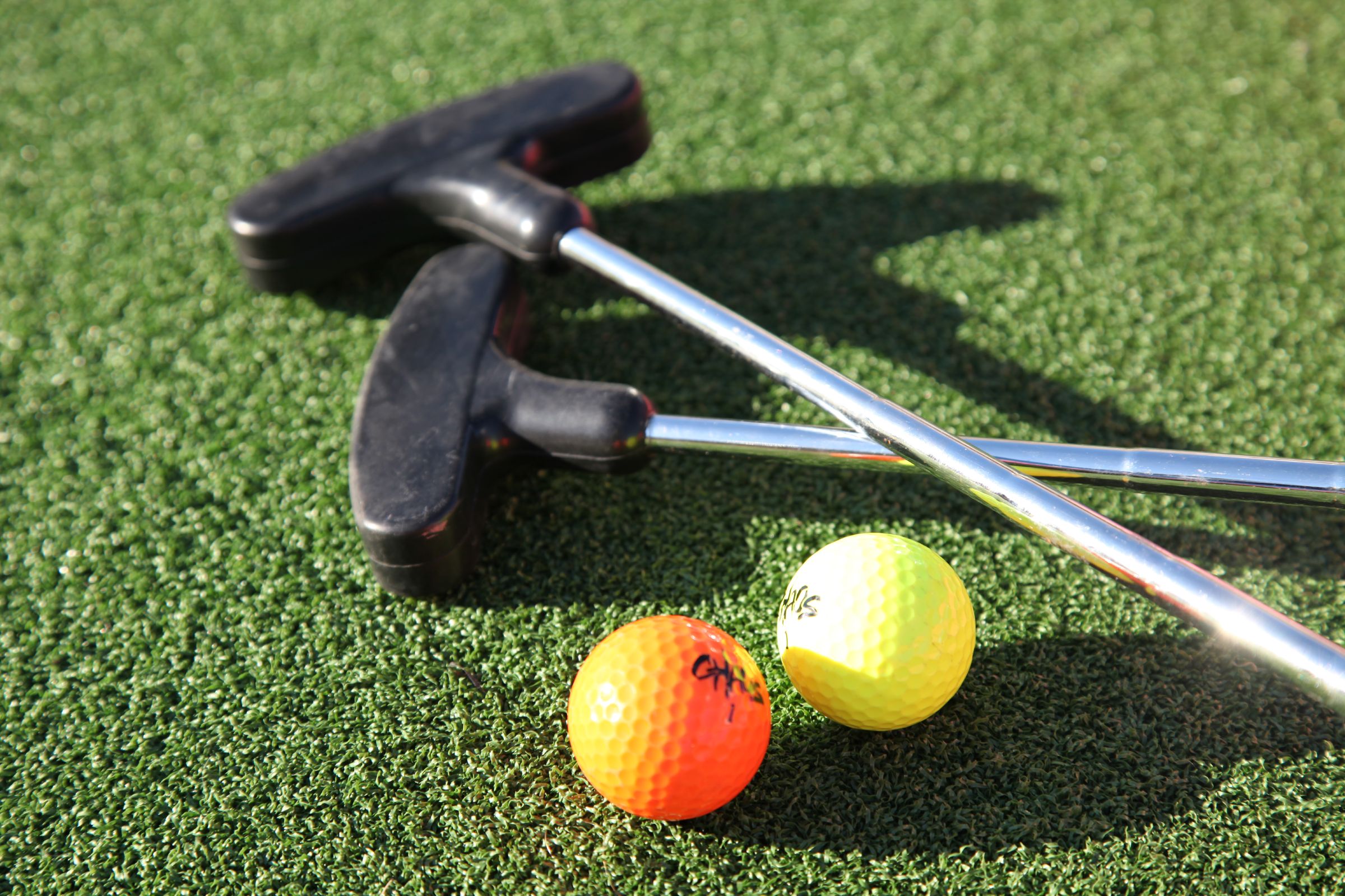 A pair of golf clubs and balls on a green surface