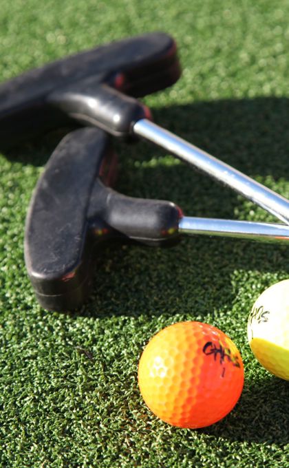 A pair of golf clubs and balls on a green surface