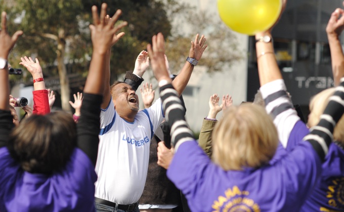 A group of people participating in a Laughter Yoga event with their hands in the air