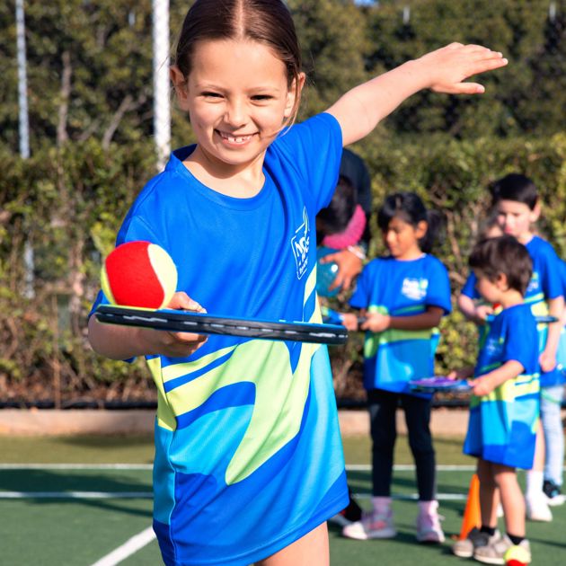 Photo of a young girl holding a tennis racquet with a red ball on it